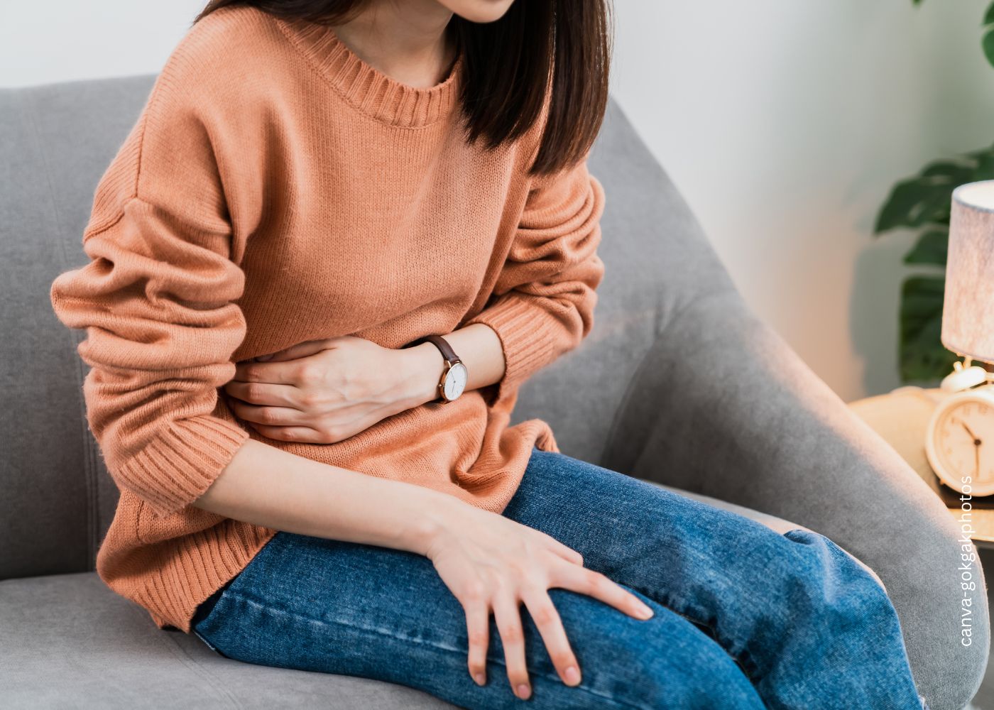 Frau sitzend mit Schmerzen im Oberbauch zum Thema Gallensteine - Was sind die Symptome